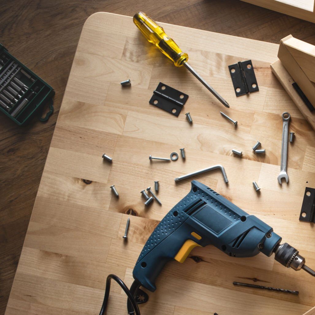 Top view of drill tool and another equipment on wood table furniture.assembly, improvement or repairing home interior concepts ideas